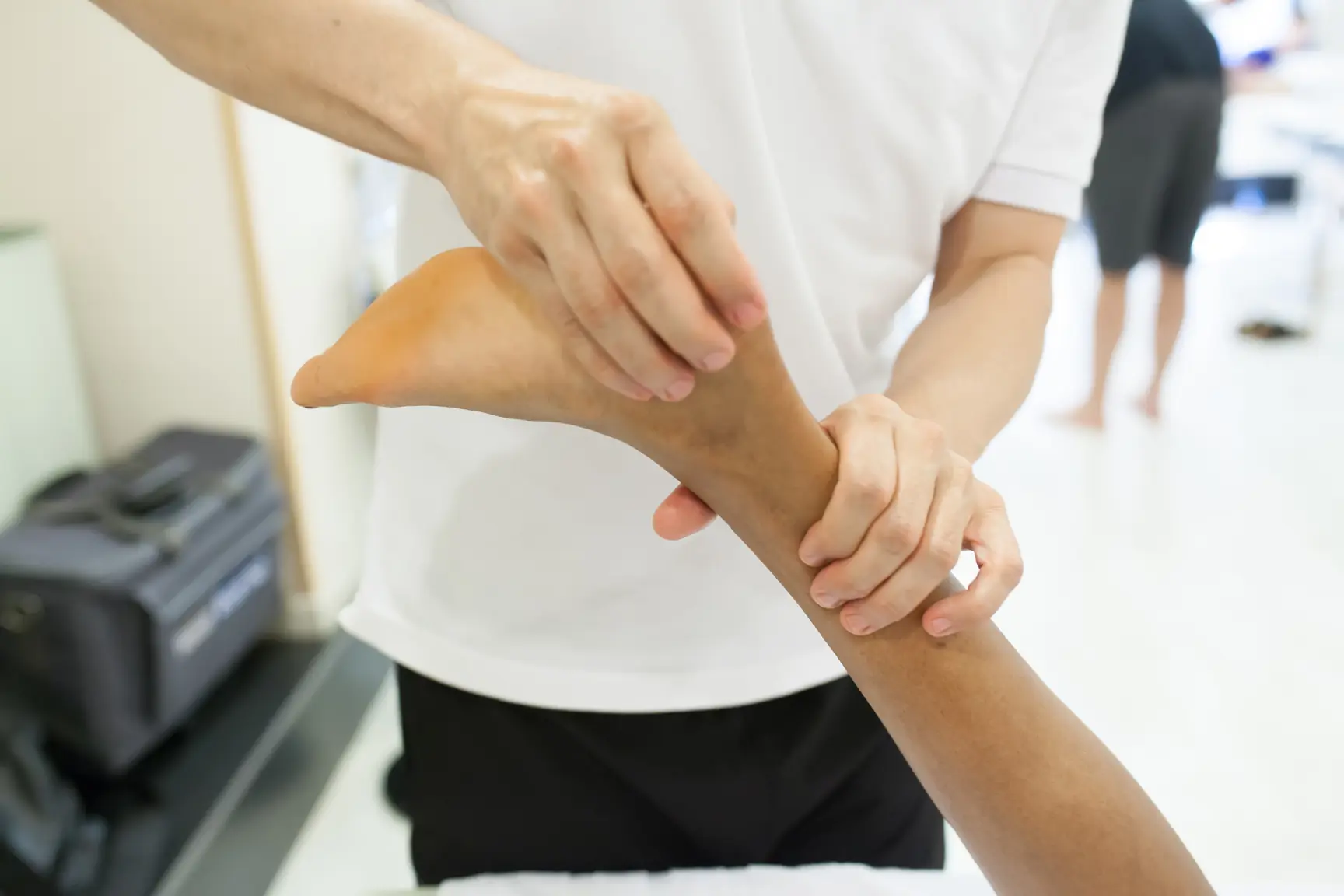 Physiotherapist examining the Achilles tendon at the back of a patient's heel