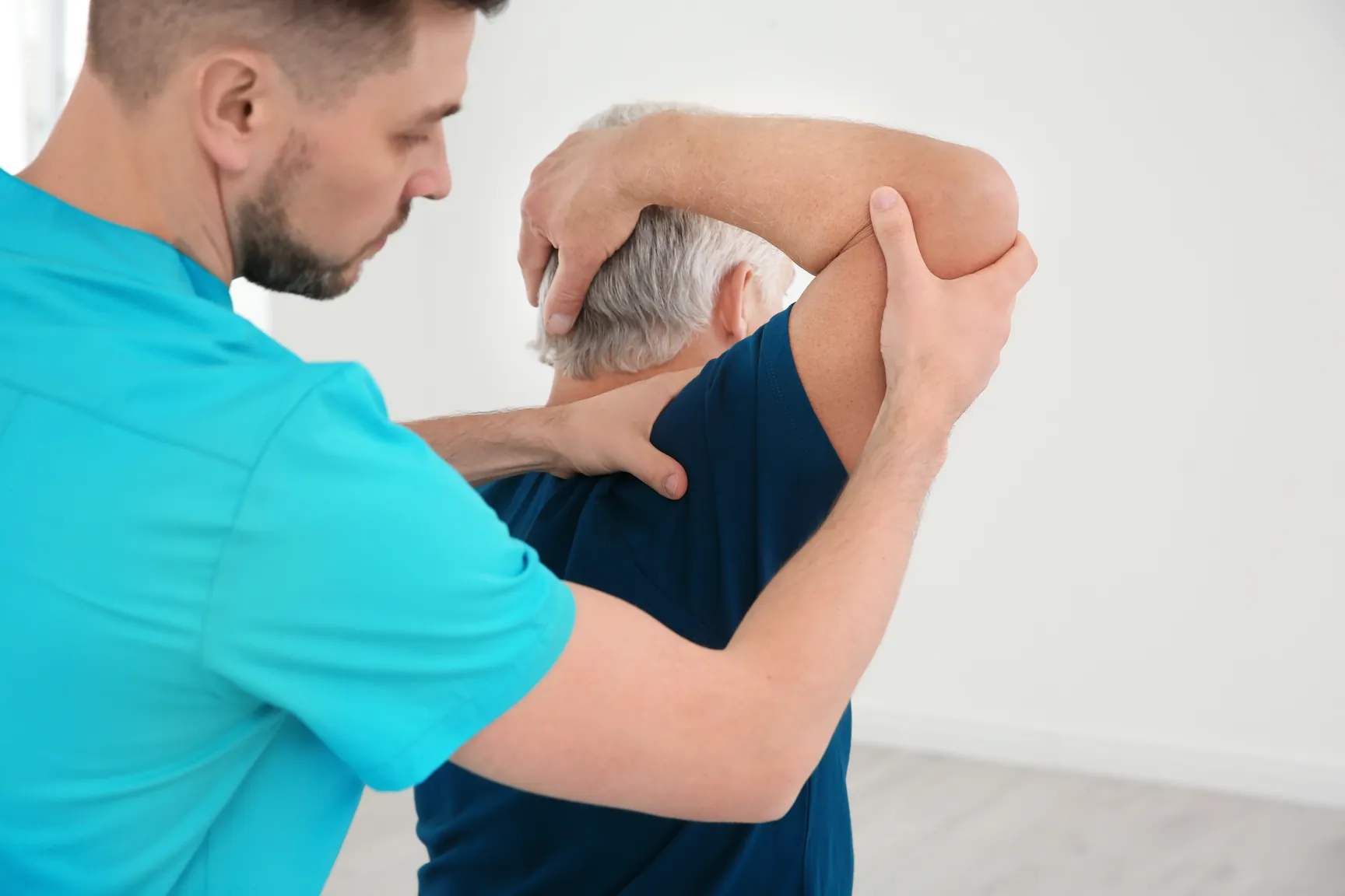 Physiotherapist gently moving a patient's arm to check shoulder movement