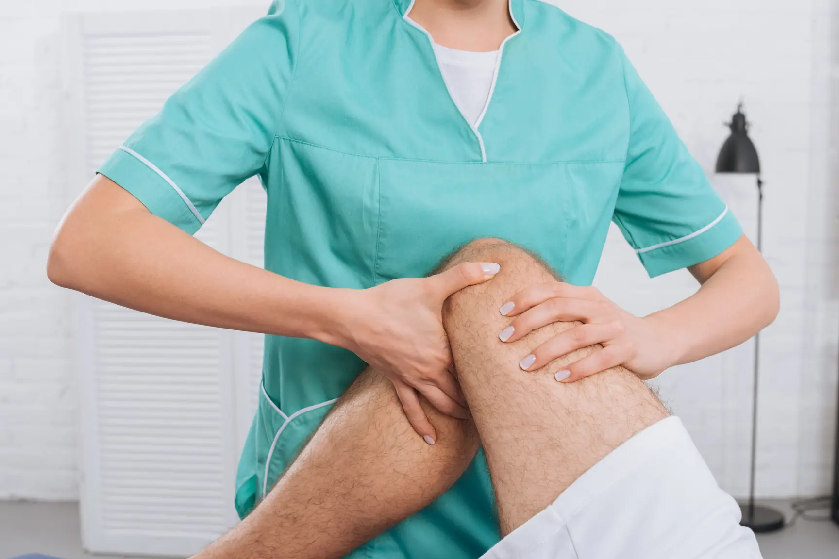 Physiotherapist examining a patient's knee on a treatment table