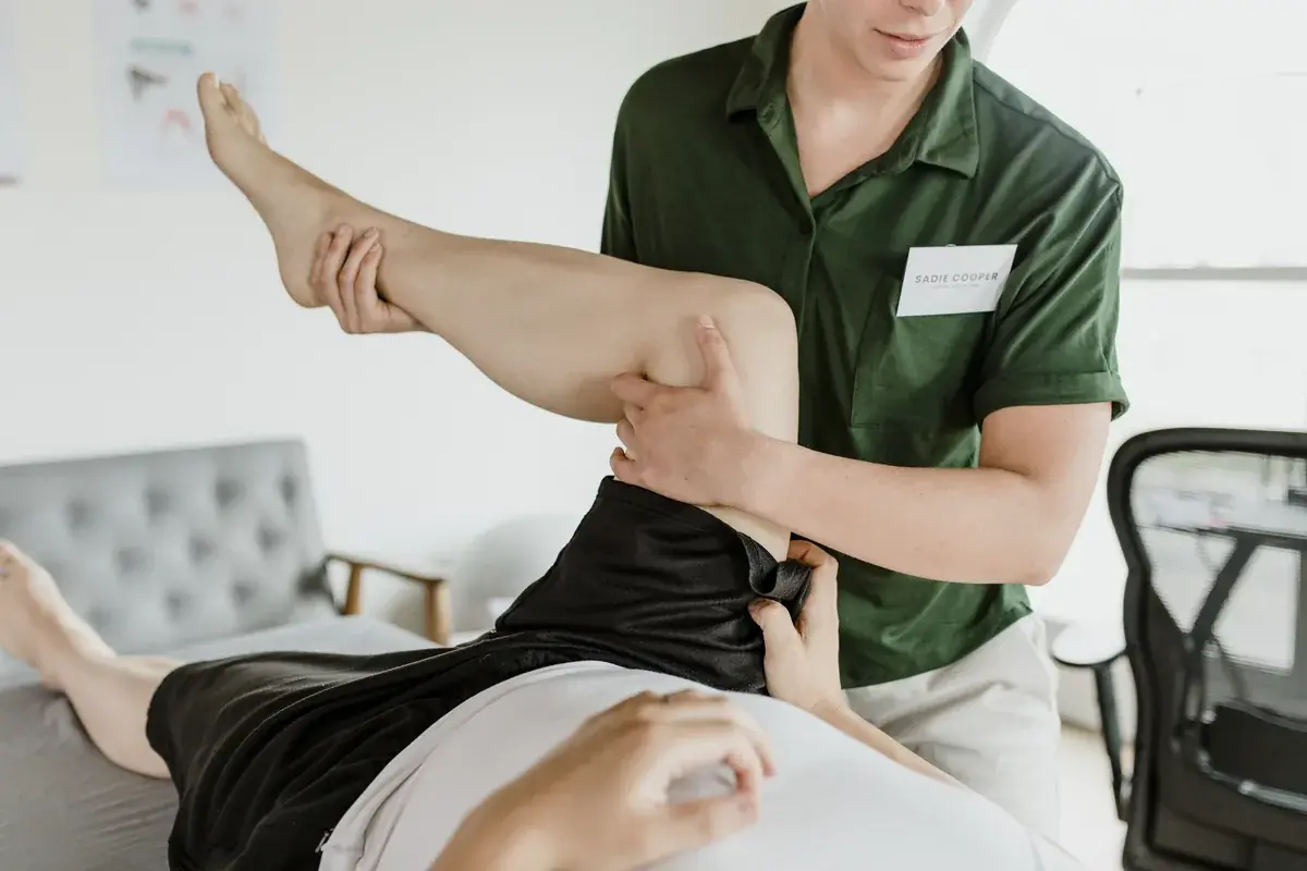 Physiotherapist guiding a patient's raised leg during rehabilitation