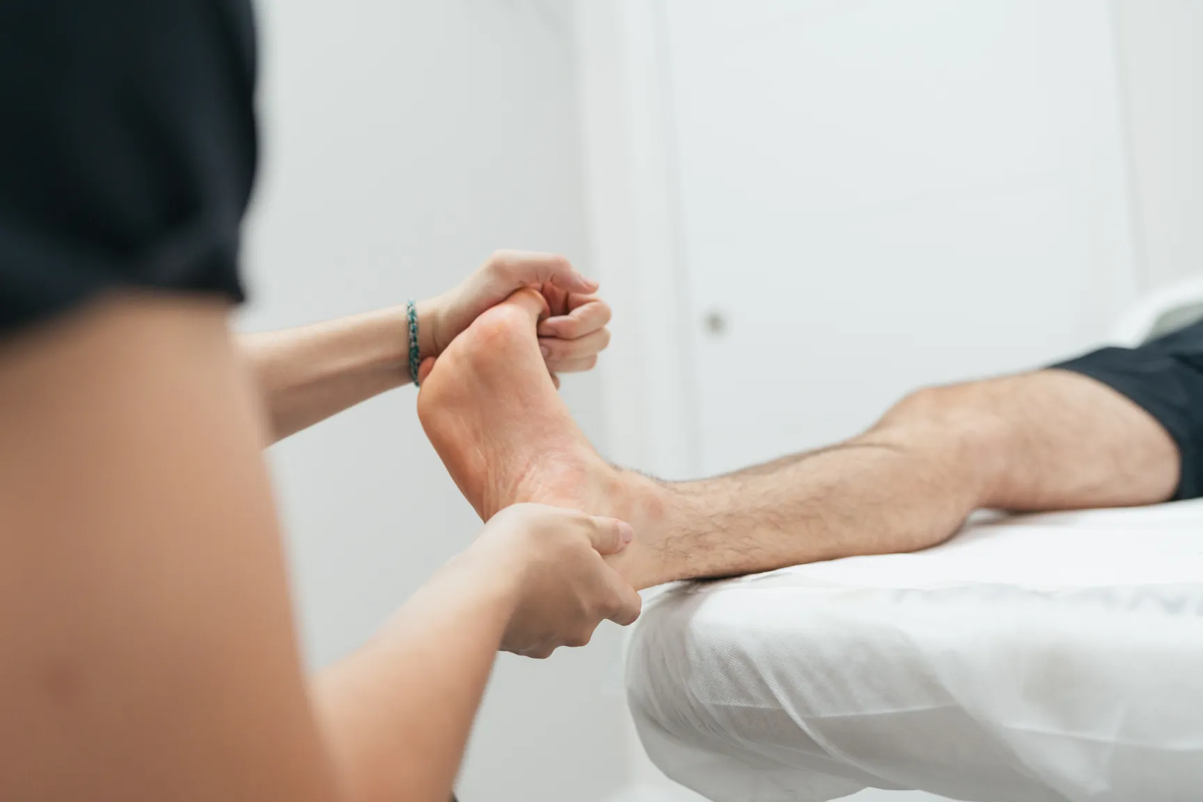Physiotherapist examining the heel and arch of a patient's foot