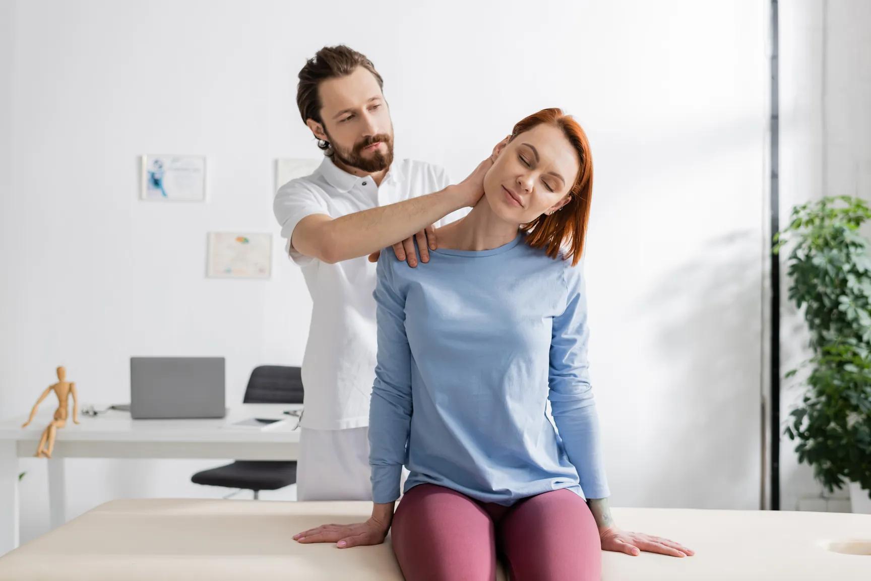Physiotherapist examining a patient's neck and upper back