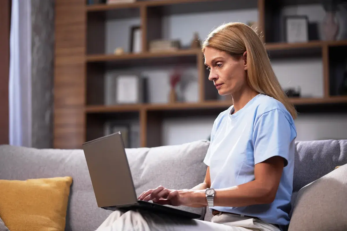 Woman using a laptop at home to describe her symptoms to PhysioMatch